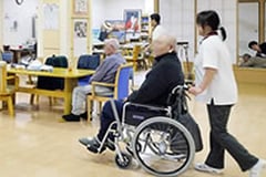 職員が利用者を車いすにて移動する様子