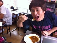 11時の昼食タイム、カレーをバカ顔で食う塾長、後ろで生徒が目を輝かせて見ている