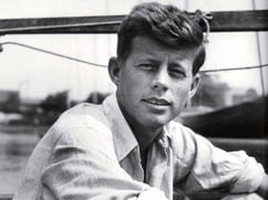 Black and white photo of John F. Kennedy as a young man in an open necked shirt
