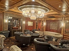 Cigar lounge in Hotel Kempinsky Riga with a crystal chandelier and white and dark grey leather sofas