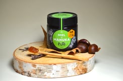 Pot d'un Miel de Manuka NPA 10+ de Nouvelle-Zélande de Puri New Zealand avec une cuillère en bois avec dedans du Miel de Manuka