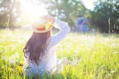 femme assise dans une prairie avec soleil