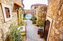 Stone-paved alley in the Ulcinj old town hotel with traditional stone houses, wooden doors, and potted plants creating a charming Mediterranean atmosphere