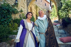Couple dressed in Cervantes and Dulcinea costumes standing in a historic stone alleyway