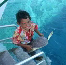 enfant portant une tortue de mer polynesie