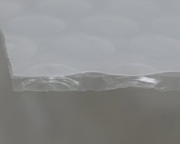 『アキレス　ウイルセーフ』をラミネートしたエアセルマットの断面。上側にある白いフィルムが、『アキレス　ウイルセーフ』。