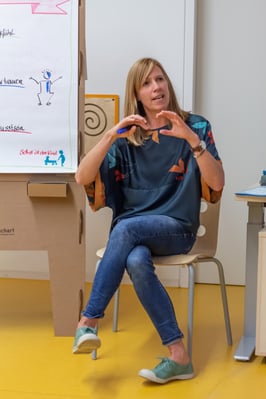 Imke sitzt neben Flipchart und spricht zur Gruppe