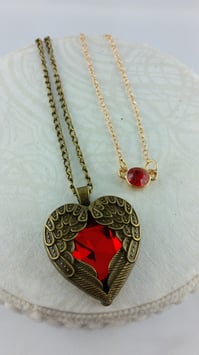 Zwei Anhänger an Ketten: "Geflügeltes Herz und kurze Kette mit kleinem roten Glasstein"