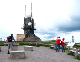 Inschrift der Tafel: Feldberg 1493 m. Sie befinden sich an der höchsten Stelle Baden-Württembergs. Hier stand um die Jahrhundertwende das Gasthaus zum Feldberg-Turm. Seit 1937 steht der Feldberg unter Naturschutz.