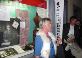 Silke Redolfi, die Leiterin des Frauenkulturarchivs vor dem ersten Schaufenster von "per ün mumaint". Es heisst BündnerinnenStolz und zeigt einen Moment aus dem Leben der Stickerin Ursula Donau-Hänny von Portein. (Bild Katharina v. Salis)