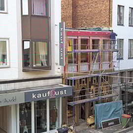 Auf diesem Foto sieht man noch im oberen Stock die alte Fassade in rot und unten bereits neue Elemente.