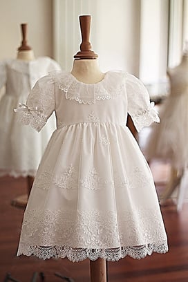 Robe baptême fille courte Sofia en tulle brodé italien blanc doublé coton. Corsage avec collerette en dentelle de Chantilly et manches resserrées par un ruban de satin. Fait-main France. Atelier Fil de Légende à Neuilly-sur-Seine. Envois France, Europe.
