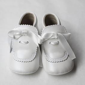 Chaussons bapteme bébé montant en cuir souple blanc cassé avec noeud en satin. Chaussons cérémonie bébé Fil de Légende. Magasin vêtements baptême cérémonie bébé Paris, Neuilly-sur-Seine.