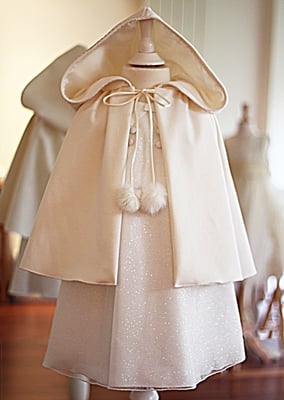 Cape cérémonie enfant laine ivoire avec large capuche. Fermeture ruban avec pompons. Fait-main France. Atelier à Neuilly-sur-Seine. Envois dans toute la France.