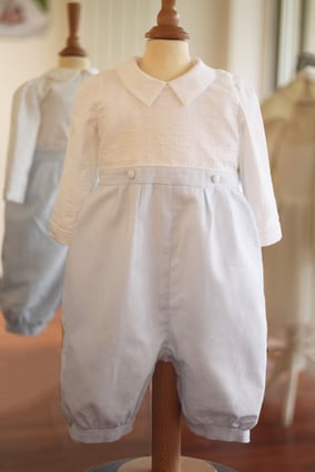 Barboteuse Hugo dé cérémonie pour bébé garçon. Corsage manches longues en coton blanc brodé avec pantalon bloomer en coton bleu ciel. Fait-main dans l'atelier Fil de Légende à Neuilly-sur-Seine. Envois dans toute la France. Magasin baptême Paris.