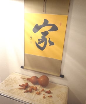 Hängende Schriftrolle mit chinesischer Kalligraphie und Kalebassen darunter. 