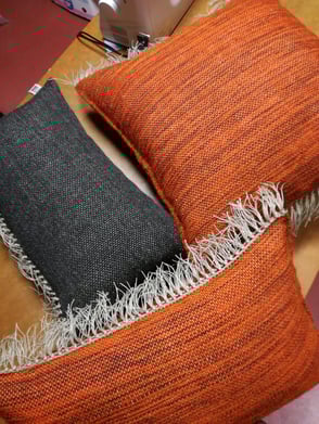 trois coussins en laine avec la frange en lin; un noir et deux orange chiné