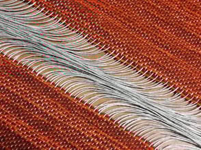 Un détail du tissage en laine chinée orange et marron, avec un rythme de fils de lin au milieu.