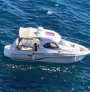 An anchored white motorboat resting in the clear blue waters of the Adriatic Sea, rented from Palata Venezia in Ulcinj
