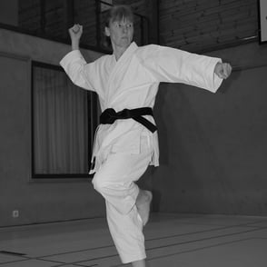 Die Karate-Trainerin zeigt eine Position aus einer traditionellen Kata (From). Sie steht dabei auf einem Bein.