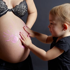 grossesse enfant qui peint ses mains sur le ventre rond de sa maman 