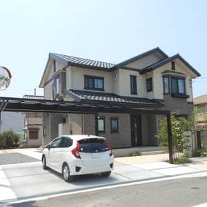 前面道路が狭いため、カーポートを梁延長仕様にすることでお車の出し入れをスムーズに、また開放感のあるファサードになりました。奥へと続く土間コンクリートは、南のタイルテラスへとつなぐアプローチであり、車椅子で移動されるご家族への優しさです。　　　　　　　　岡山市北区　H様邸　フラワーチルドレン　エクステリア