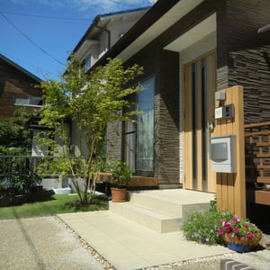 玄関ドアに素材感と色目を合わせた機能門柱を立て、足元は植栽スペースに。ナチュラルな感じが出ます。　　　　　　　岡山市北区Ｍ様邸　エクステリア　フラワーチルドレン