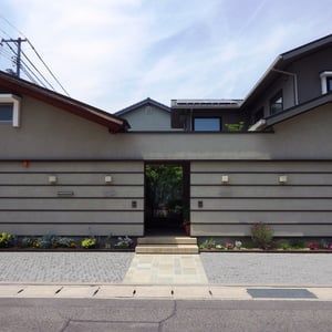 築7年のニ世帯住宅のアプローチと駐車スペース。来客はまず玄関でガラス越しに庭を眺め、それぞれ通されたリビングからも庭を眺めることができる素晴らしい住宅の構成。外構に出来ることは？。ご相談を受けた時は悩みましたが、出した結論は『建築のデザインを邪魔しない。』すなわち『外構のデザインを後でしたように見えないようにデザインする。』という事でした。新築当初からこの外構であったと言っても不思議には思われない仕上がりになったと思います。　　　　　　　　　　　　　　　岡山市北区　K様邸　フラワーチルドレン　エクステリア