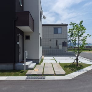 訪問者は横から入り、郵便物を投函したりインターフォンを押したりする動線にしています。砂岩を貼ったアプローチは側溝からあえて段差を付け、蹴上げはモルタル仕上げにし、シンプルな印象に仕上げました。　シラカシの足元はマウンドを作り、直線的なラインが多いデザインを引き立てる為の、曲線的なポイントにしています。　　　　　　　　　　　　　　　　　　　　　　　　　　　　　　　　　　　　　　　　　　　　　　　　　　　　　　　　　　　　　　　　　　　　　　　　　　　　　　岡山市北区　S様邸　エクステリア　フラワーチルドレン