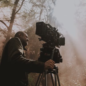photo lors d'un tournage du directeur de la photographie manu dacosse avec sa camera et le soleil qui crée un effet cinématographique