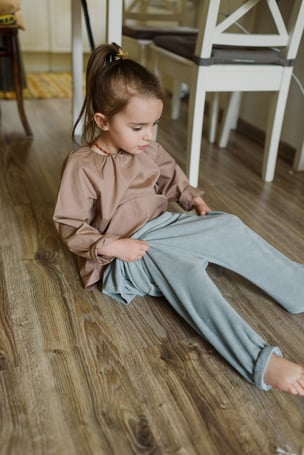 Kind zieht sich am Boden die Hose an