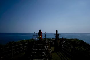 夜の岬（み・さき）から海原を眺める女性。静かな一人時間。