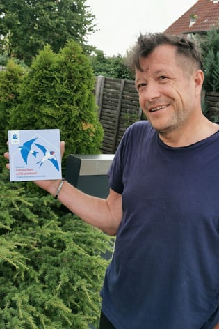 Herr Kahl aus Cadolzburg mit der Plakette "Schwalbenfreundliches Haus" (Foto: Hans-Georg Müller)