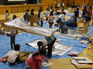 宿泊体験の一環として、アルミ蒸着ラミネート・エアセルマットや段ボールを利用して、就寝スペースを作り上げる子どもたち。