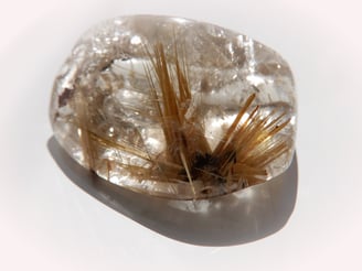 Rutilquarz - Zahlreiche feine Rutilnadeln sind als Einschlüsse in diesem transparenten Quarz-Cabochon zu sehen.