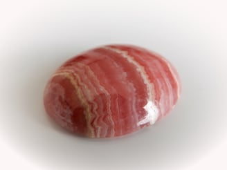 Rhodochrosit - Die natürliche Bänderung dieses Kiesels verleiht diesem Stein ein gestreiftes Ercheinungsbild.
