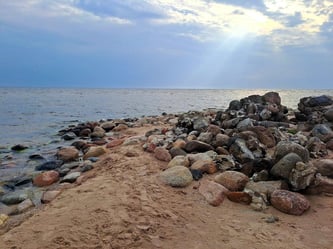 Rocky tip of Cape Kolka in Kurzeme, Latvia, with a ray of sunshine bursting through grey clouds