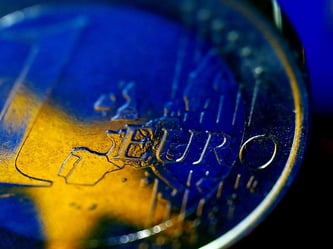 Die Fahne der Europäischen Union (EU) spiegelt sich in einer Euro-Münze. Foto: Oliver Berg/Illustration