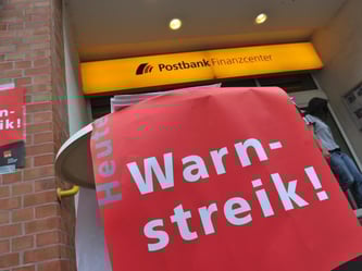 Warnstreik-Plakate hängen in Berlin an einer Filiale der Postbank im Stadtteil Tegel. Foto: Paul Zinken