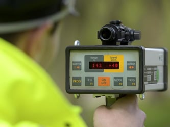 Polizeibeamter misst die Geschwindigkeit der vorbeifahrenden Autos. Foto: Alexander Körner/Archiv