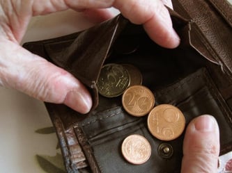 Eine Frau hält eine nahezu leere Geldbörse in den Händen. Foto: Jens Kalaene/Illustration