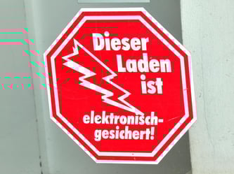 Ein Aufkleber «Dieser Laden ist elektronisch gesichert!». Foto: M. Schutt/Archiv