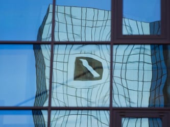 Verzerrt spiegelt sich in Frankfurt am Main das Logo der Deutschen Bank in einer Glasfassade. Foto: Frank Rumpenhorst/Illustration
