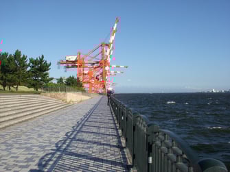 立ち並ぶ青海埠頭のガントリークレーン。向こうの空には、羽田空港へ着陸する飛行機が飛び交う。