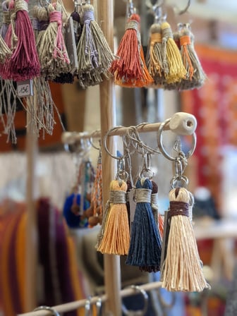 Les porte-clés en forme de glands en lin naturel et lin coloré sont suspendus sur un présentoir en bois.