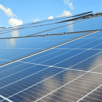 Foto eines Daches bedeckt mit Photovolatikmodulen, bleuer Himmel bei Sonnenschein