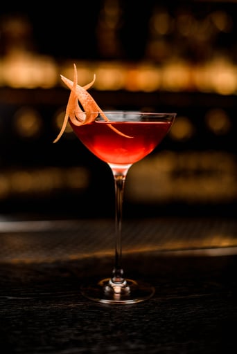 Negroni Cocktail mit Orangenschale mit Lichtern im Hintergrund. 