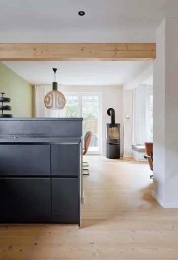 Ein altes Backsteinhaus in Hamburg erstrahlt durch die Kombination aus alten Elementen, wie der Holzbalkendecke und modernem Mobiliar, wie der schwarzen Küche und frischen Farben in neuem Glanz.