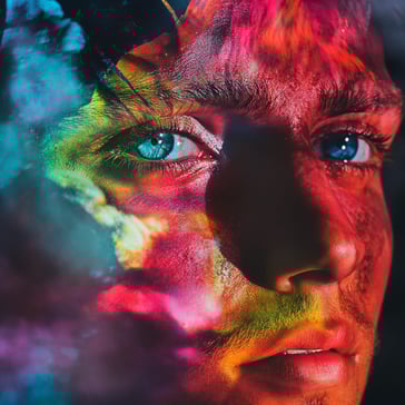 Ein farbenfrohes Foto des Gesichts eines jungen Mannes mit blauen Augen, mit Doppelbelichtungseffekt, vor dunklem Hintergrund, farbenfroh und lebendig, detailliert und im surrealistischen Stil, aufgenommen mit einer Sony Alpha A7 III-Kamera.