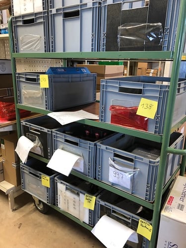 Foto vom Auftragswagen mit mehreren Kisten, in welchen sich die Teile für neue Aufträge befinden